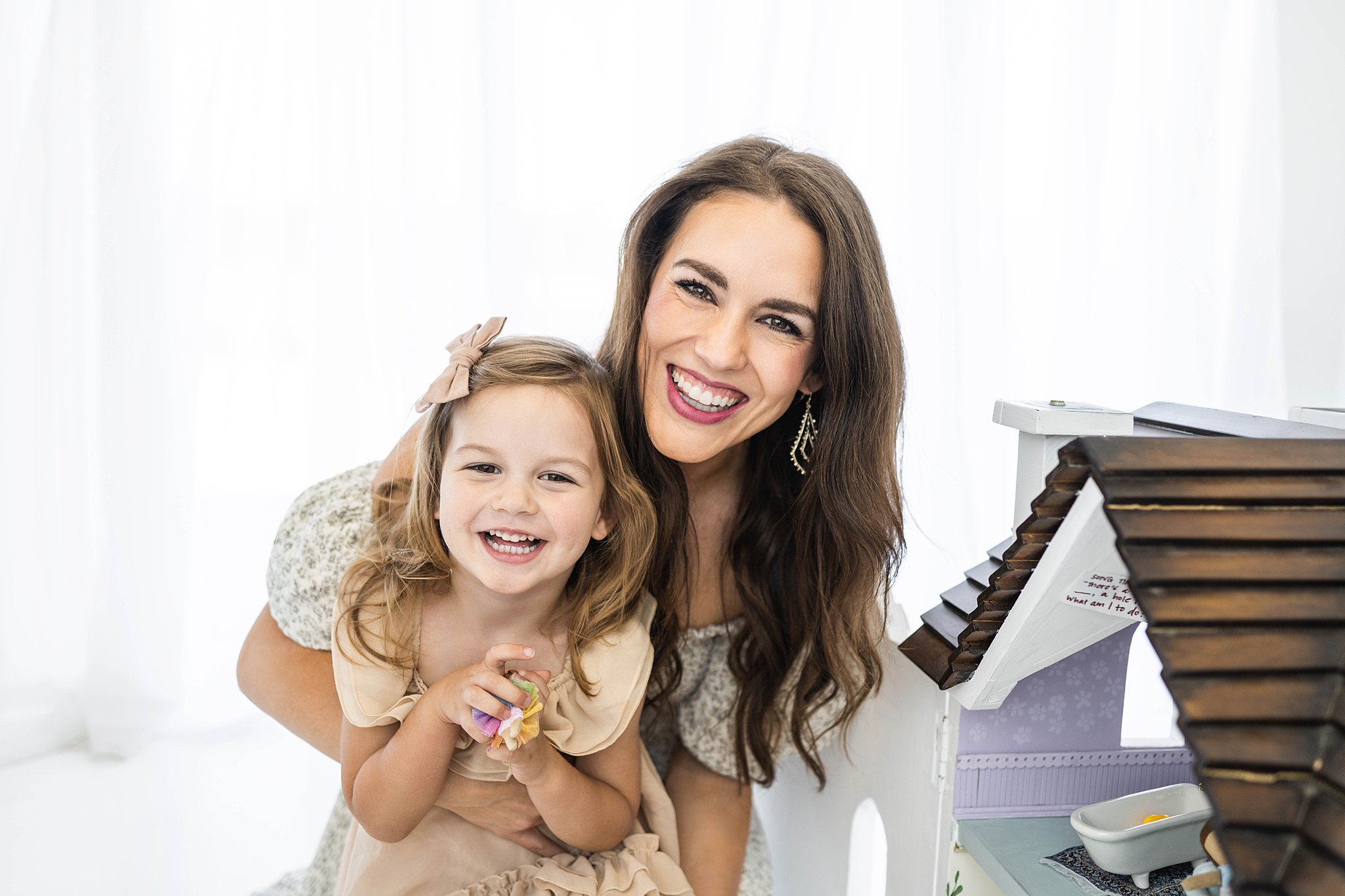 A mother and daughter play with a dollhouse in front of a window in a studio Keedo Kids