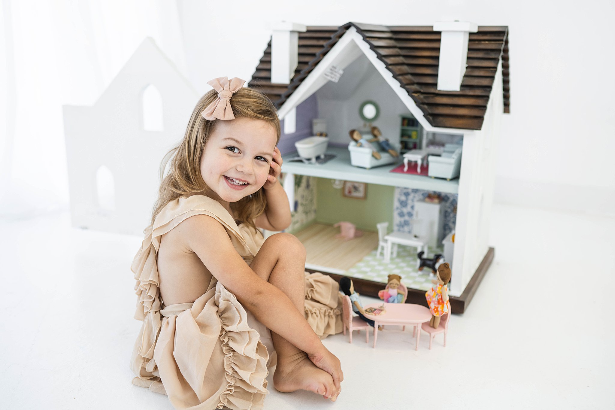 A young girl in a beige dress sets up a dinner table for a playhouse in a studio oklahoma city toy stores