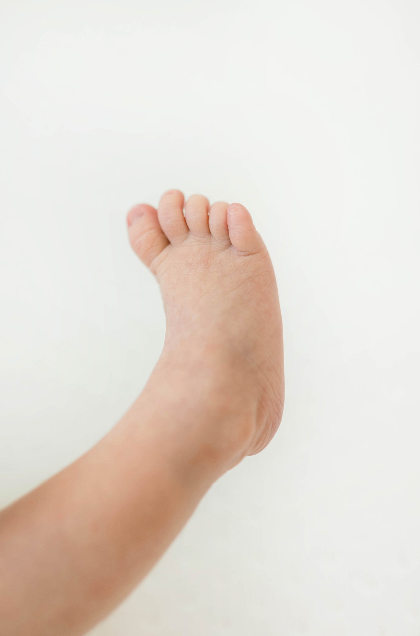 A baby foot sticks into the air of a white room