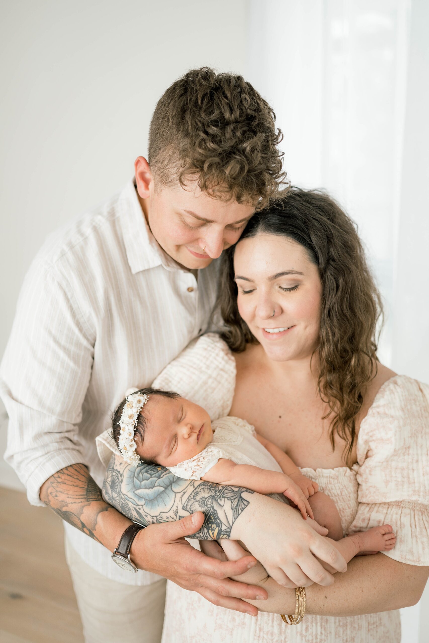 A mother cradles her newborn baby while standing and leaning into her husband's chest postpartum doula okc