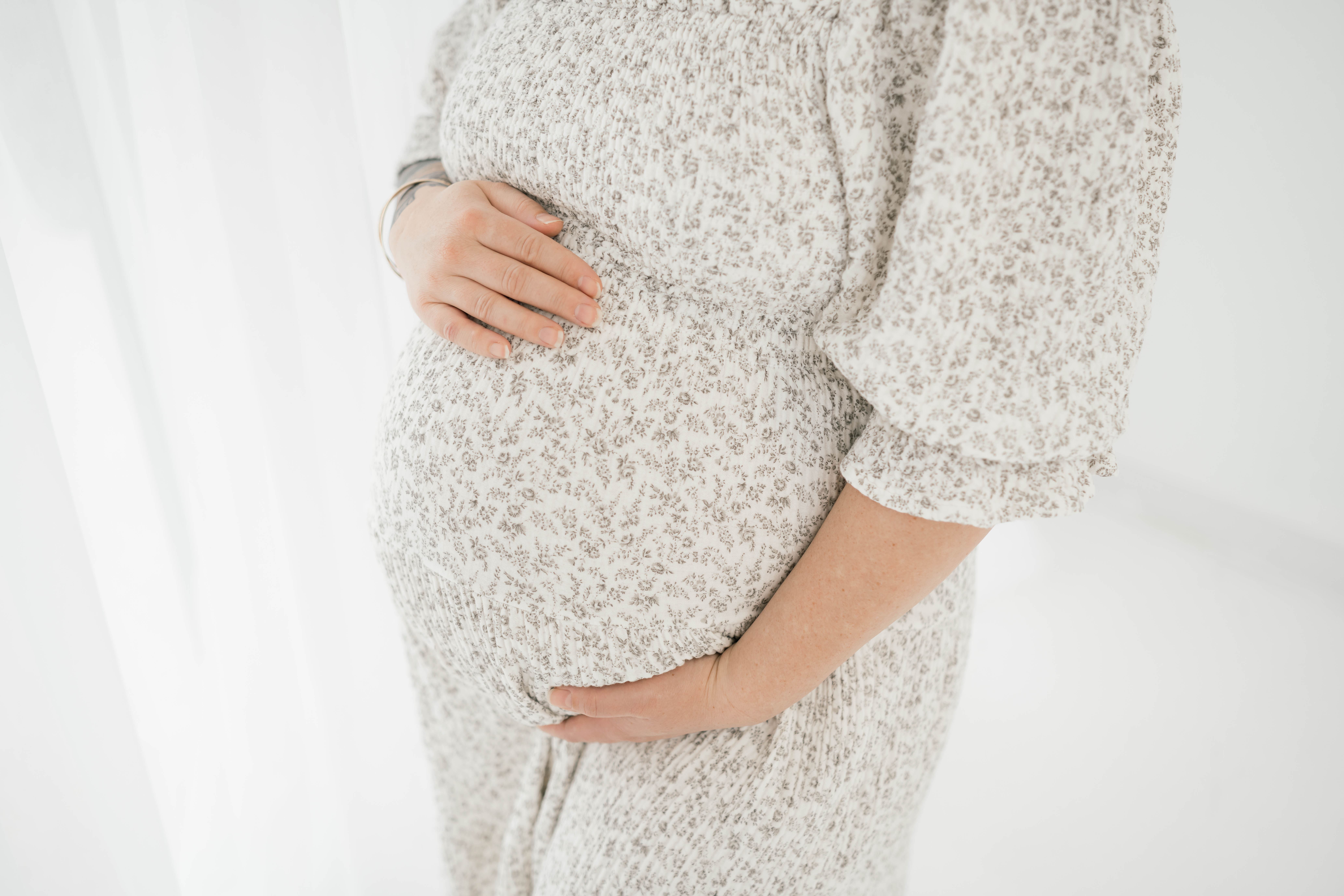 Details of a mother standing in a studio holding her bump prenatal chiropractor okc