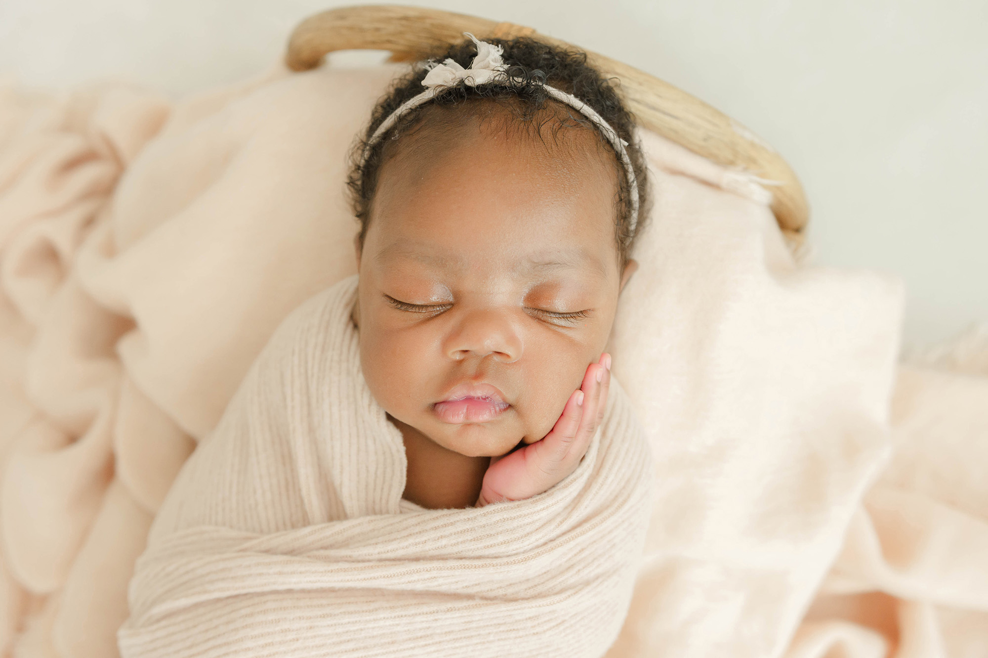 A baby sleeps with a hand on her cheek in a tiny wicker bed thanks to birthing classes in okc