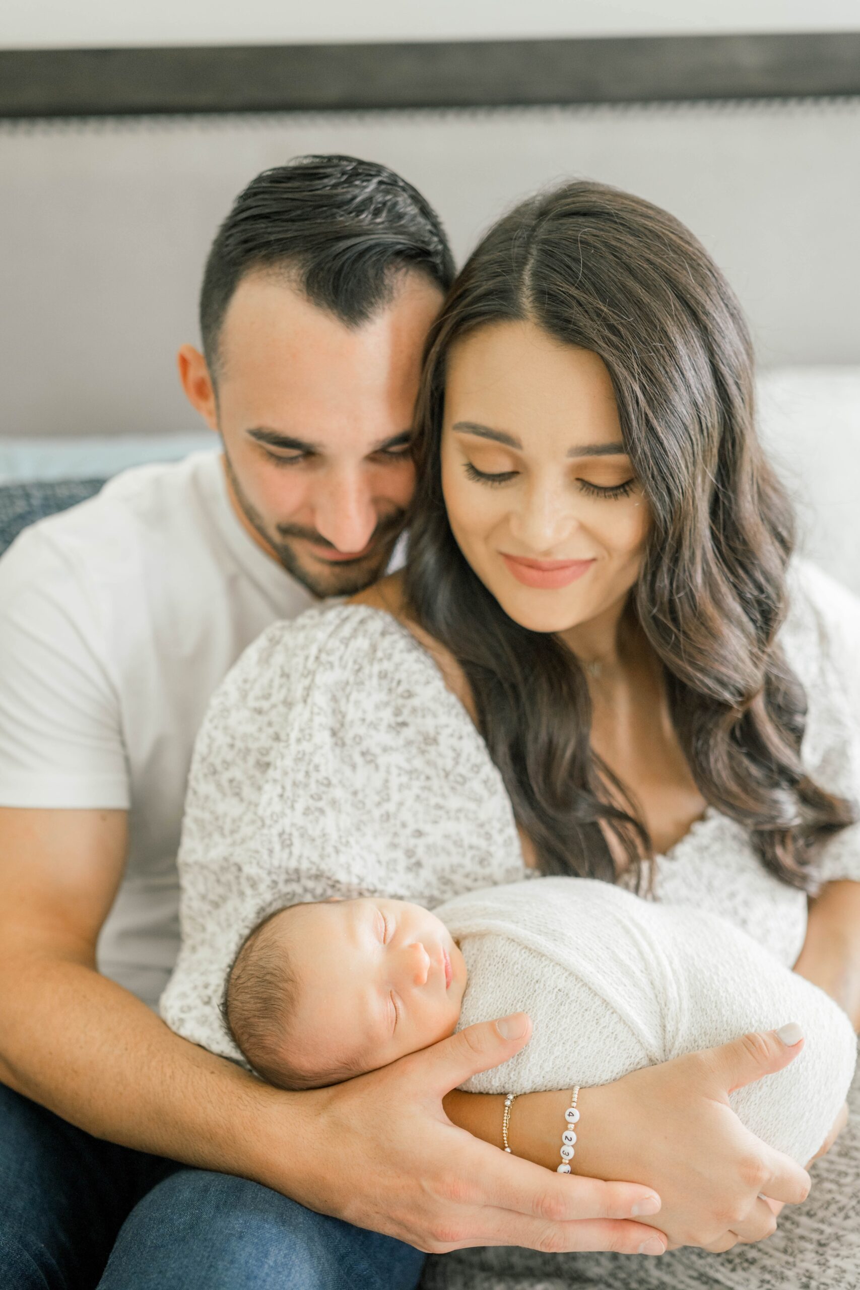 A happy mom and dad smile down at their sleeping newborn in mom's arms after finding a day spa okc