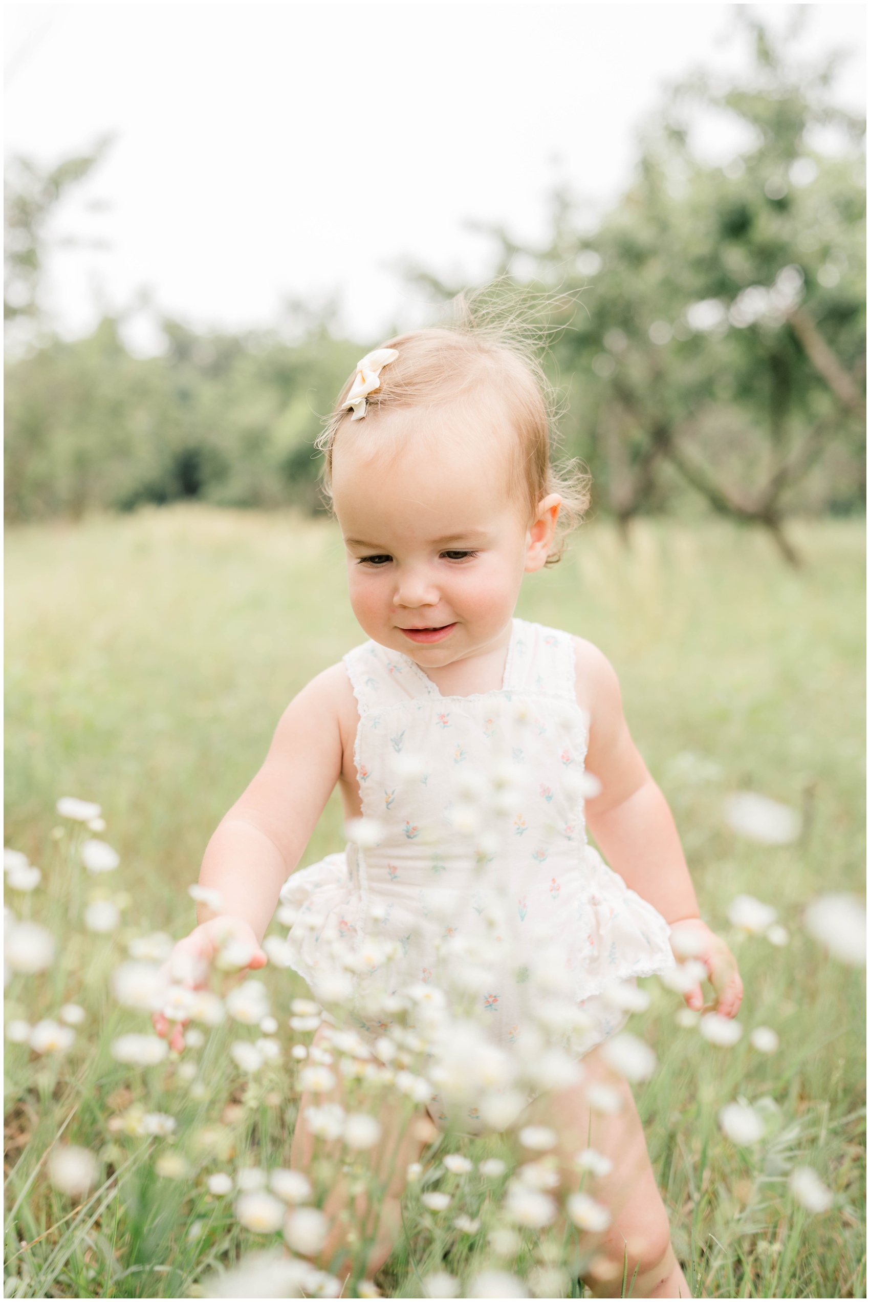 A baby girl in a white onesie wanders through a field of wildflowers before visiting fall festivals in okc