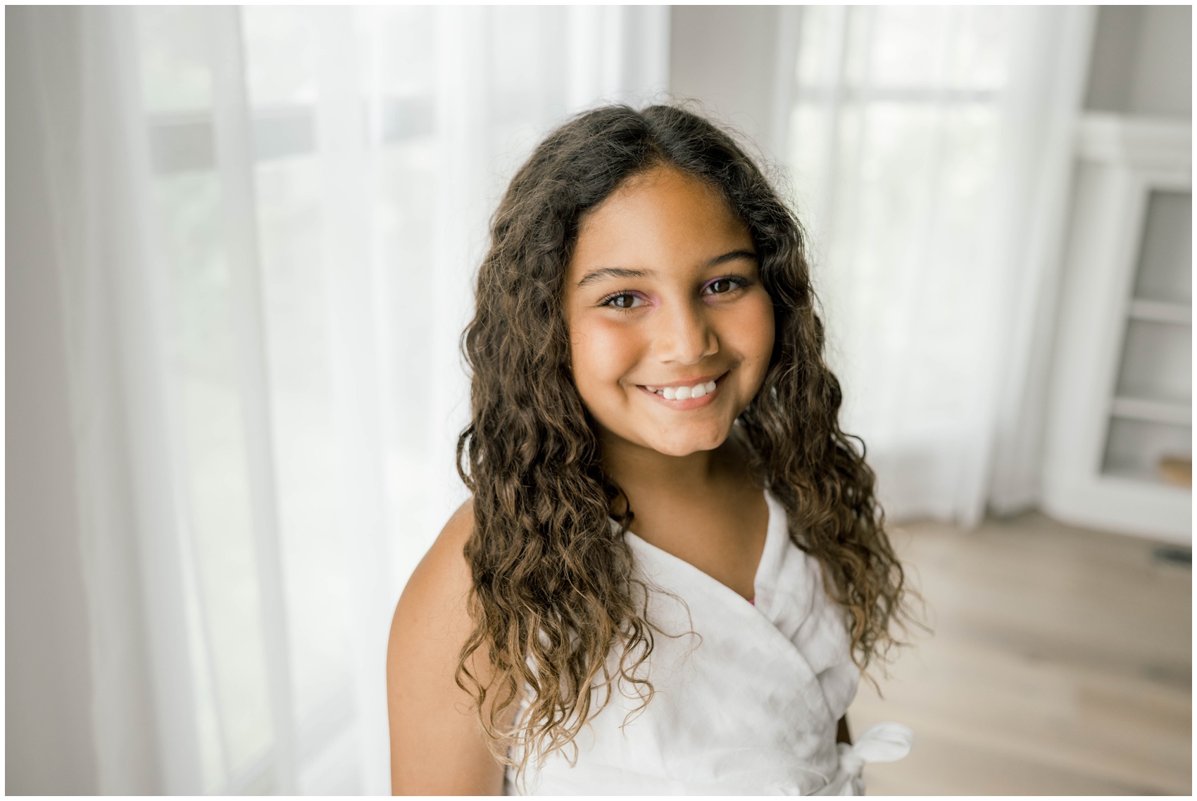 A happy young girl stands in a studio smiling in a white dress after some family counseling in okc