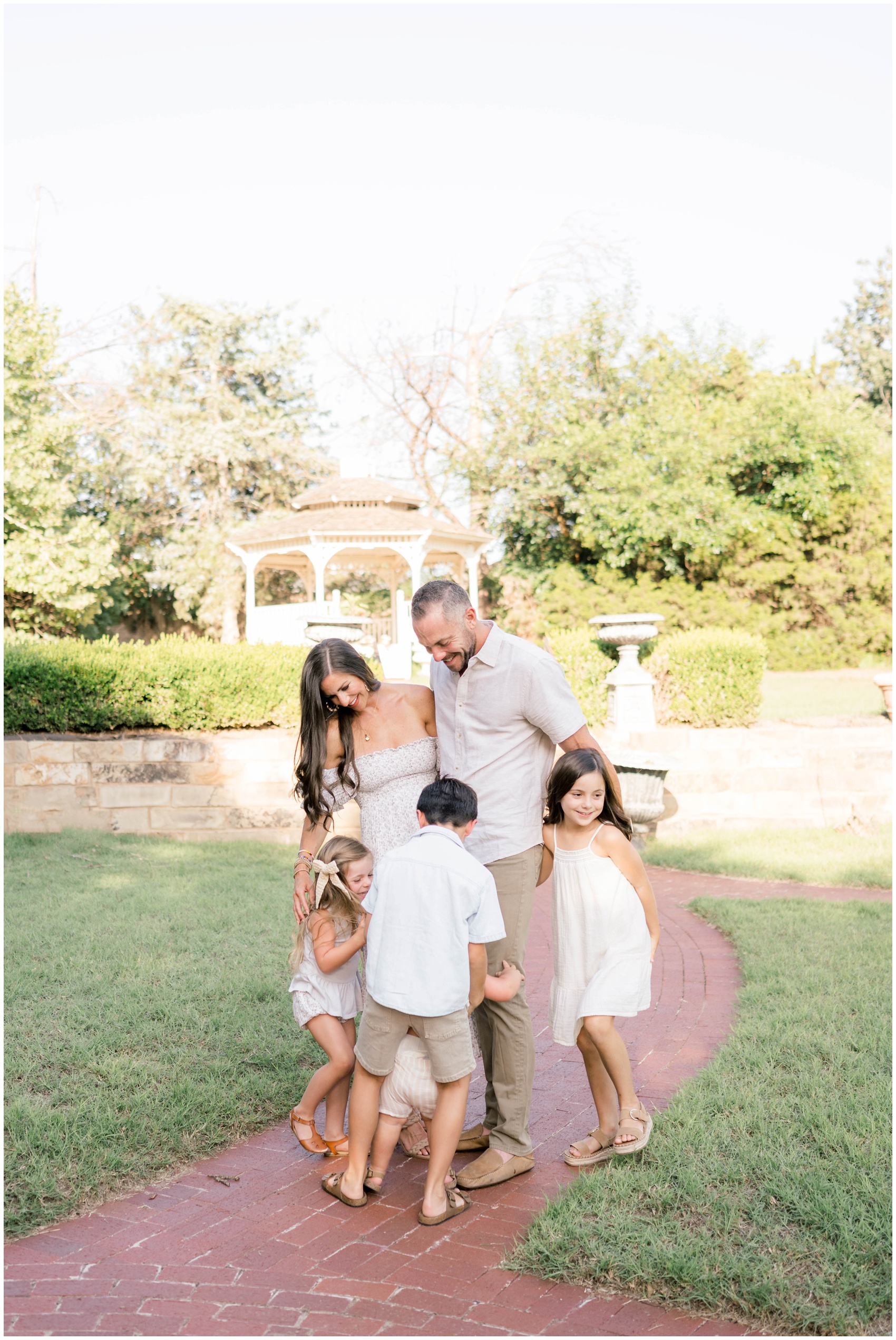 A happy group of 4 siblings hug and laugh their parents in a garden path at kid friendly hotels in oklahoma city