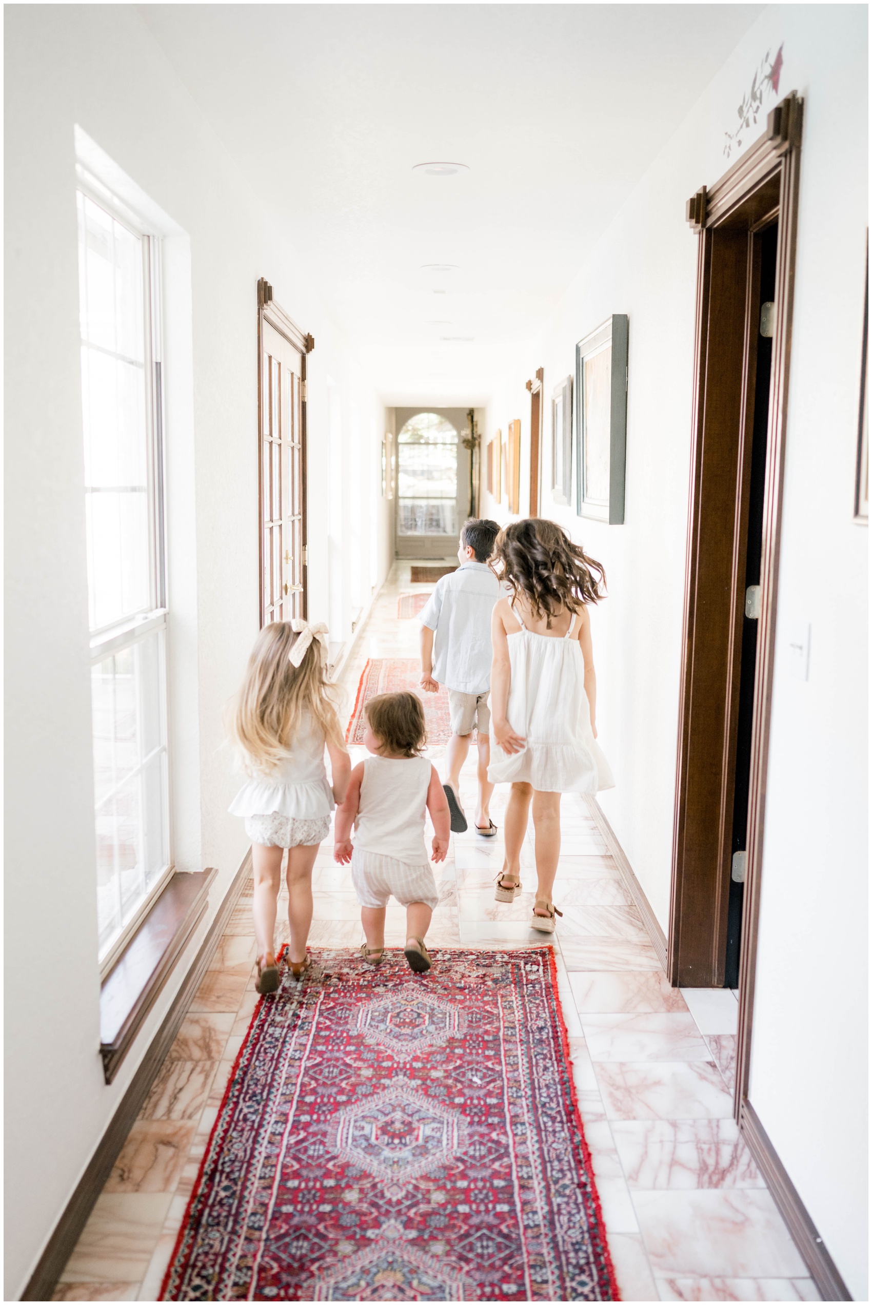 Four siblings walk together down the hall in white outfits while visiting kid friendly hotels in oklahoma city