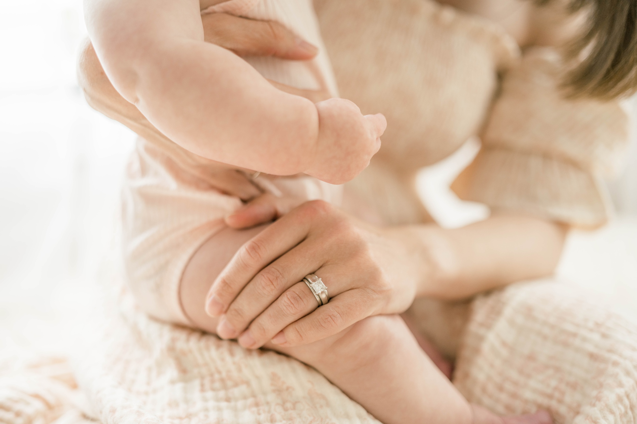 Details of a mom's hand on her baby's leg in her lap