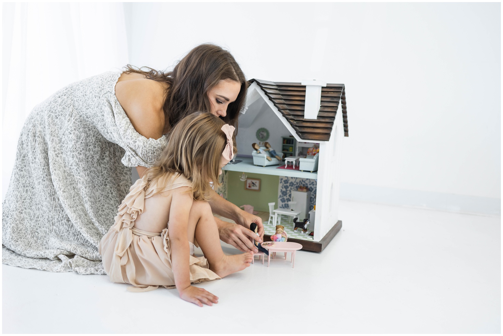 A mom and her toddler daughter play with a dollhouse in dresses after visiting montessori schools in okc