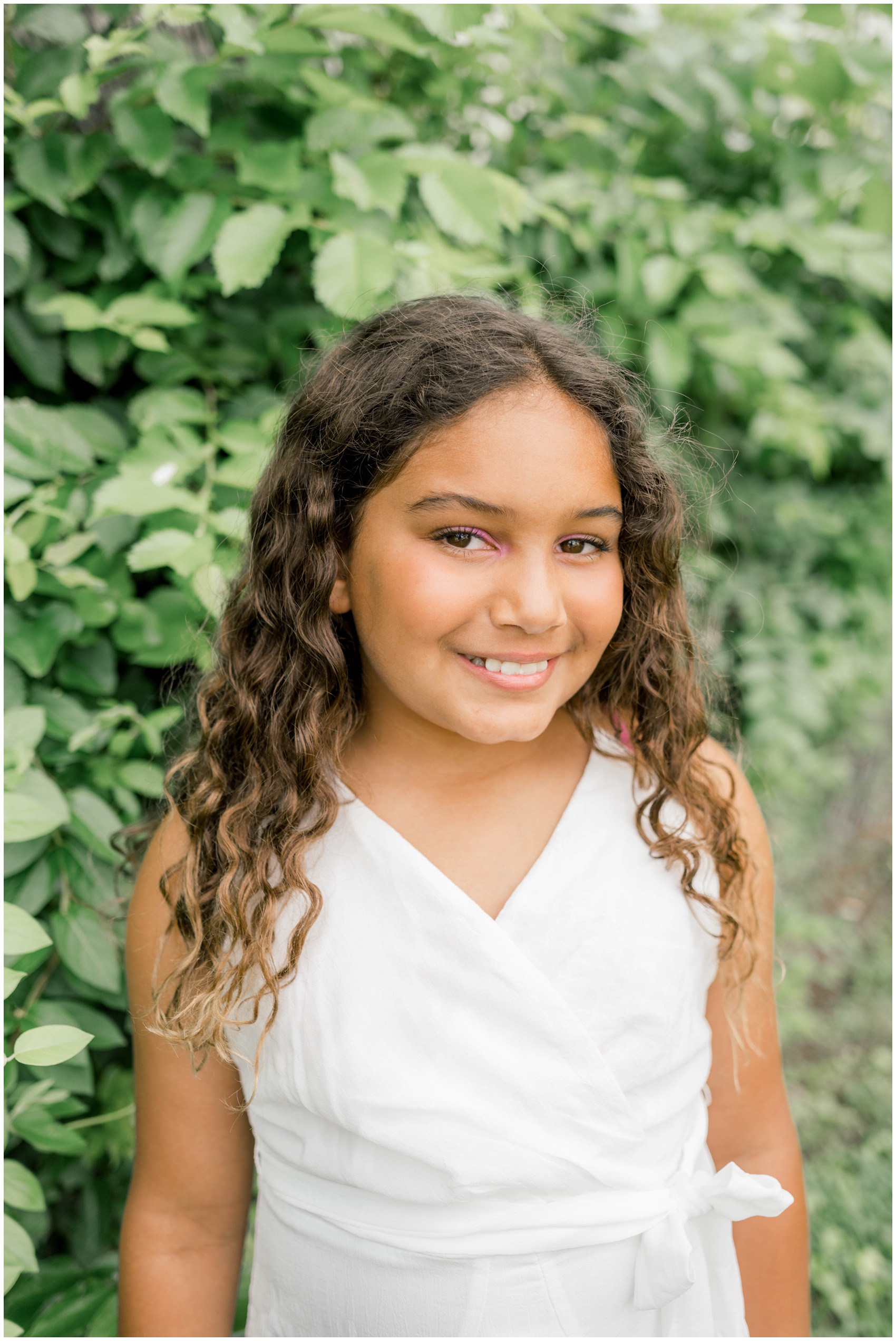 A young girl in a white dress smiles while standing in a garden before visiting private schools in okc