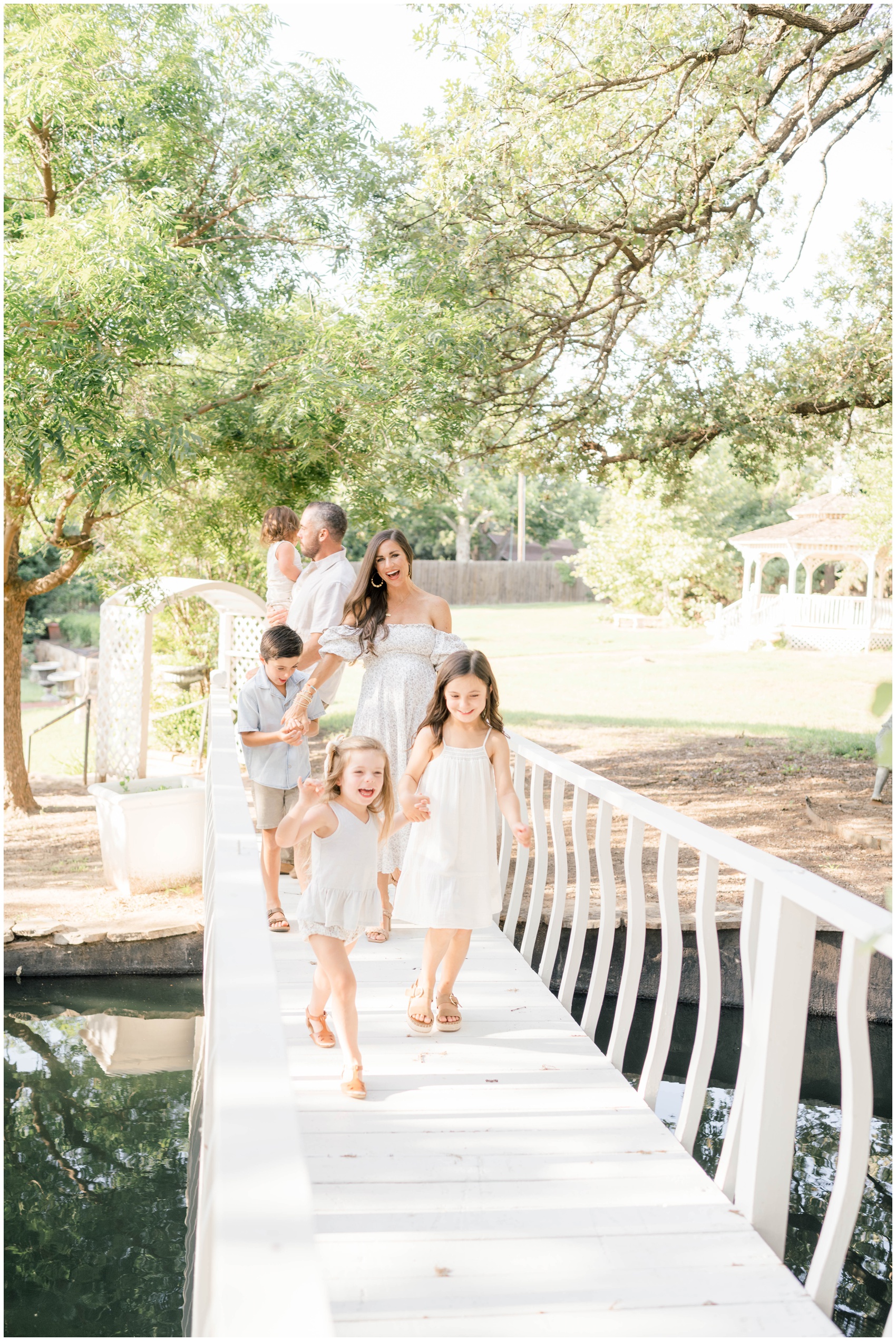 A happy family of 6 laugh and walk across a wooden pond bridge in a park before some things to do in oklahoma city for new years eve