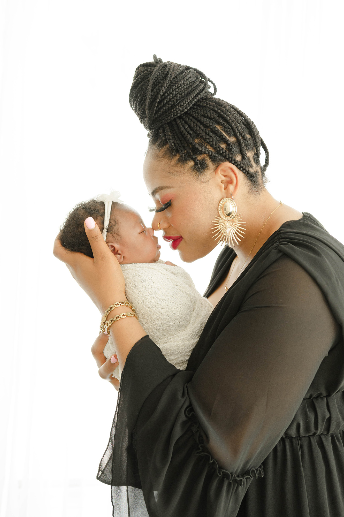 A mom boops noses with sleeping newborn daughter in a studio in black dress after visiting tin lizzie's okc