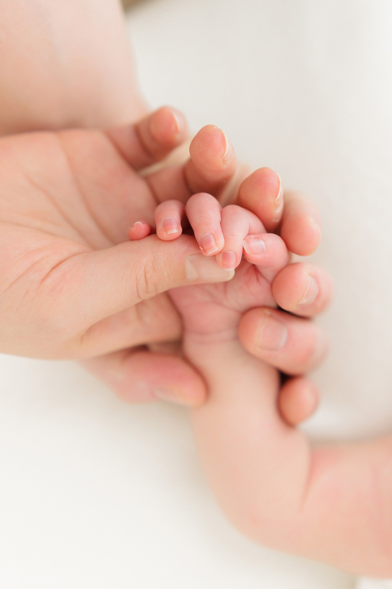 a mom holding her babies hands during the best age for newborn photos