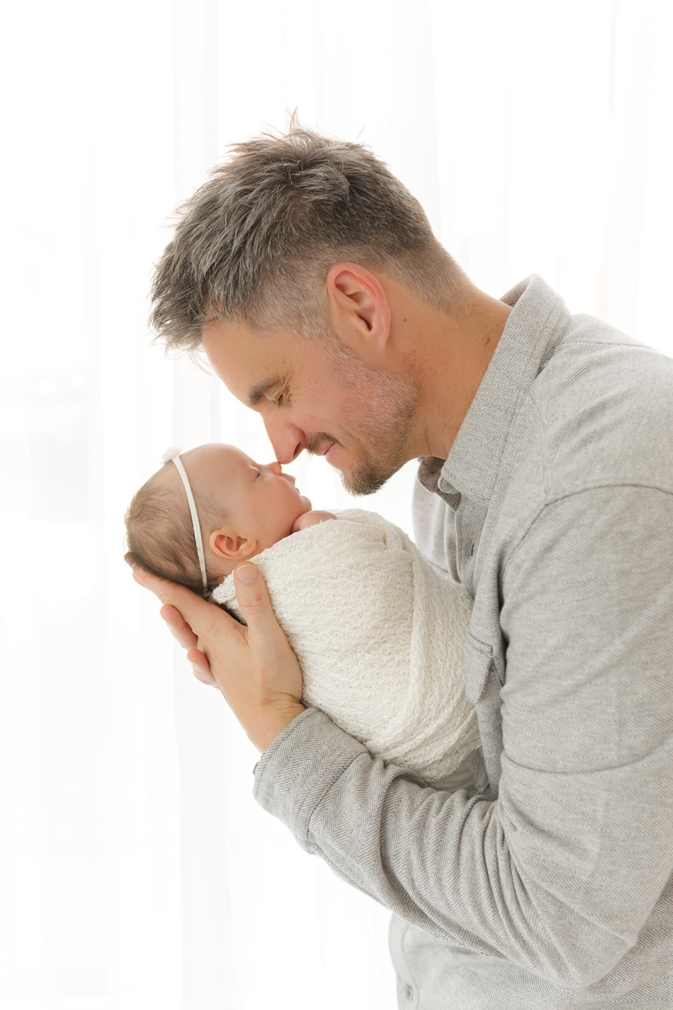 a dad holding his baby for a photo for the newborn photo album